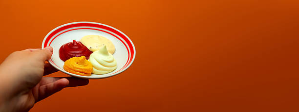 istock A captivating banner image featuring a hand holding a white plate with samples of various dipping sauces, ketchup, mustard, mayonnaise, garlic sauce. Copy space 2243852464