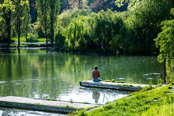 Bucharest, Romania – April 29, 2023: Man sitting by the water and relaxing in the Tineretului park, springtime.