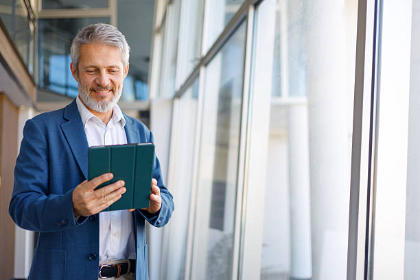 istock Businessman smiling, holding digital tablet in modern office environment, connecting with distant colleagues or clients 2243855445