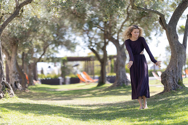 istock Woman dancing barefoot on grass among olive trees 2243855504