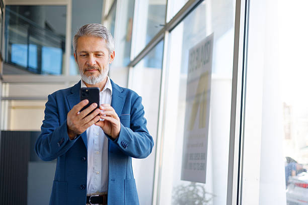 istock Mature businessman working remotely on smartphone in modern office building or airport, using digital technology 2243855558