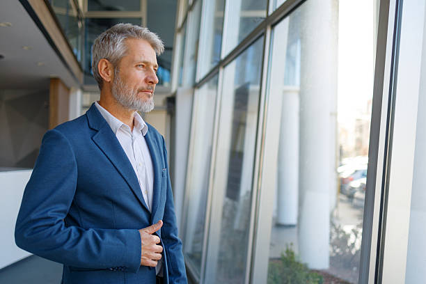 istock Mature businessman contemplating future, looking out office window with pensive expression 2243856614