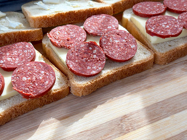 Close-up of sausage and cheese slices on toast bread. Preparing toast for breakfast