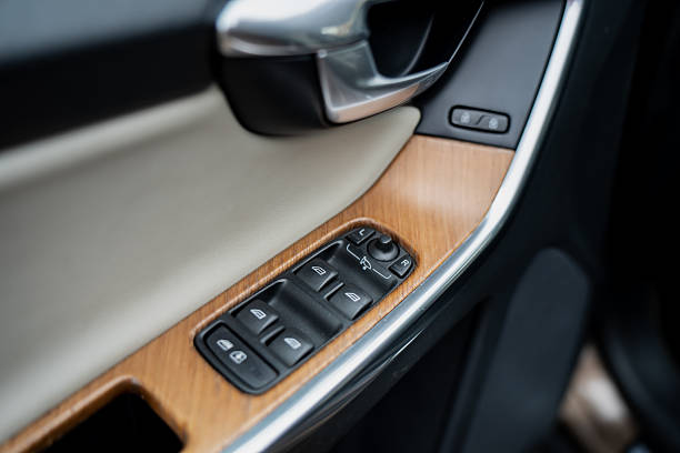 Modern car door panel with wooden trim and control buttons for windows and mirrors showcasing premium automotive interior materials and ergonomic design layout