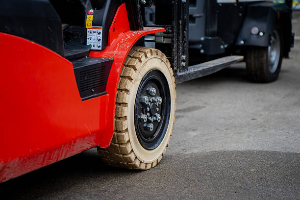 istock Red industrial forklift with beige solid tire and steel rim operating on concrete surface showing durable construction, load-bearing design, and precision engineering for warehouse use 2243857086