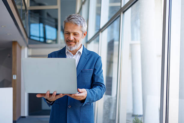istock Mature businessman working on laptop in modern office, finding solutions and connecting with clients 2243857440
