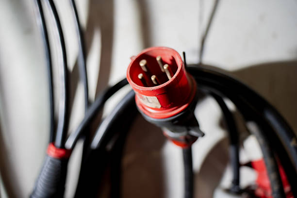Industrial red electrical connector with thick black wiring representing reliable energy connection, safety, and functionality in professional workshop or construction settings