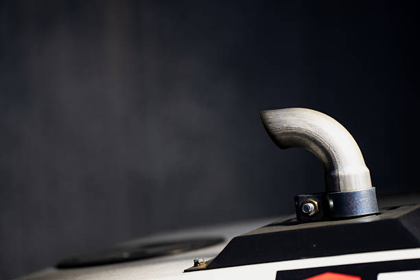 Curved stainless steel exhaust pipe outlet mounted on industrial generator surface illustrating durable metal fabrication, mechanical precision, and engineered functionality