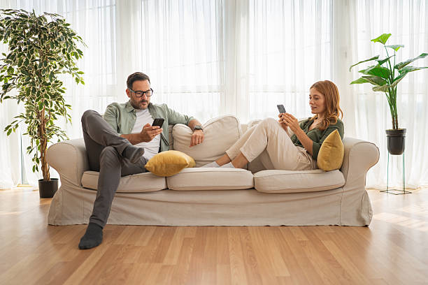 istock Couple ignoring each other focusing on smart phones on sofa 2243858652