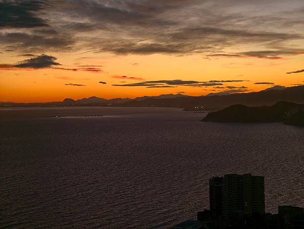 vibrant coastal skyline at dusk, urban waterfront with striking sunset and moody atmospheric effects
