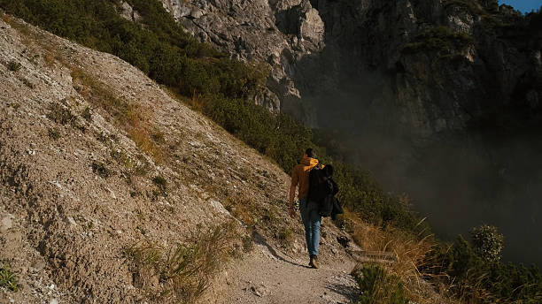 istock Man walking along a rugged path beside steep cliffs in an outdoor adventure scene during the day 2243864157