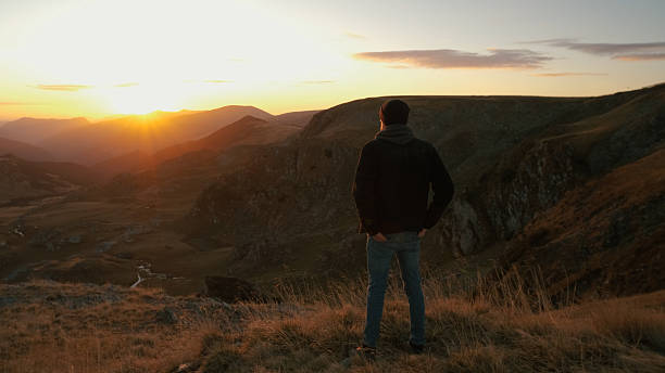 istock Man enjoying a sunset view over mountains and valleys in a remote landscape during evening hours 2243864859