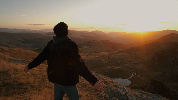 istock Man enjoying the sunset view on a mountain while standing with arms open, embracing nature s beauty after a long hike in the evening 2243865239
