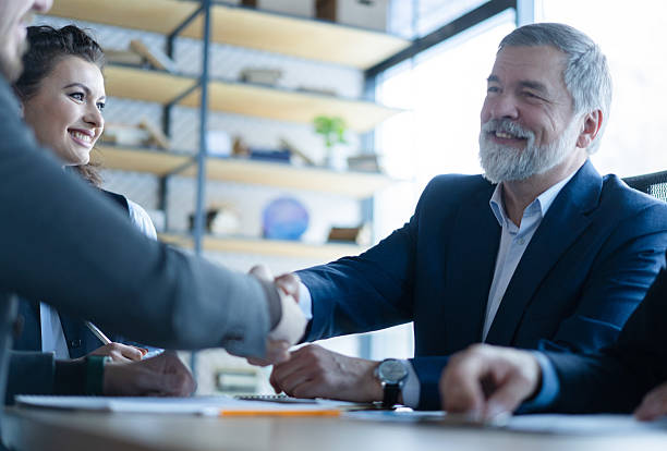 istock Happy businessmen shaking hands at group board meeting 2243865278