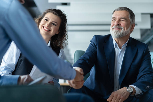 istock Happy businessmen shaking hands at group board meeting 2243865416