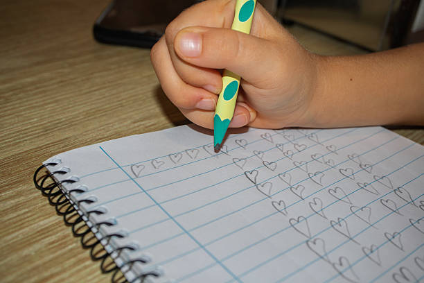 istock Child hand drawing heart shapes on notebook paper 2243867164