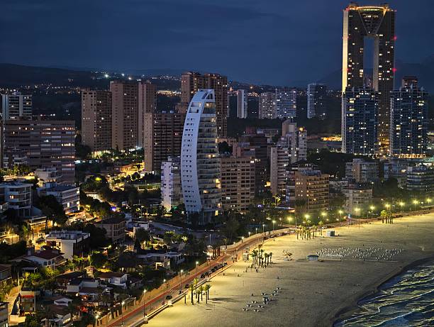 captivating drone shot of sleek hotel with glass extensions illuminated against twilight skyline