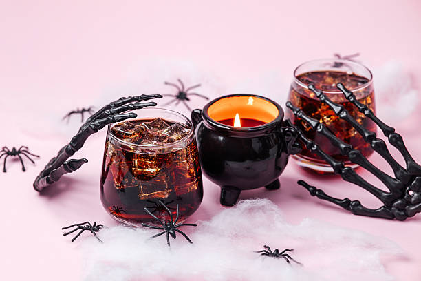 istock Halloween drinks and spooky candle surrounded by plastic spiders and skeleton hands on pink 2243874969