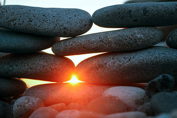 Sunset shining between stones on the seaside coast with bright light breaking through smooth rocks and creating an atmosphere of calmness and coziness