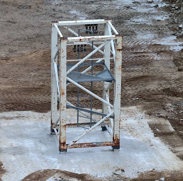 rusty steel framework in construction site, oxidized metal section standing on concrete foundation