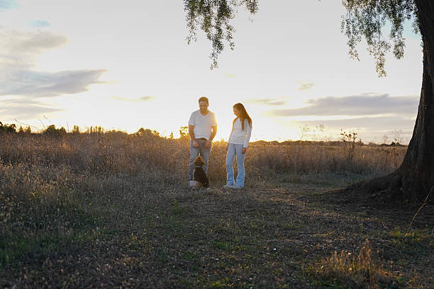 Couple and dog enjoying outdoors together in a rural setting looking at sunset