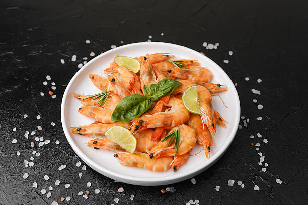 istock Shrimp with herbs and coarse salt on black surface for cooking background or seafood concept 2243879574