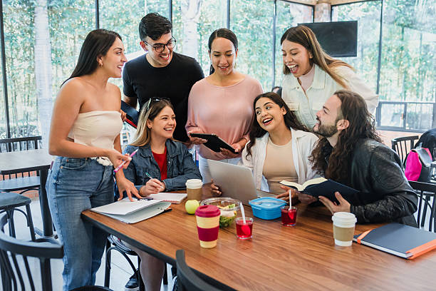 istock Group of Latino university students gathered together studying in cafeteria using laptop and notebook at breakfast time. young hispanic people woman and men in Mexico Latin America 2243882164