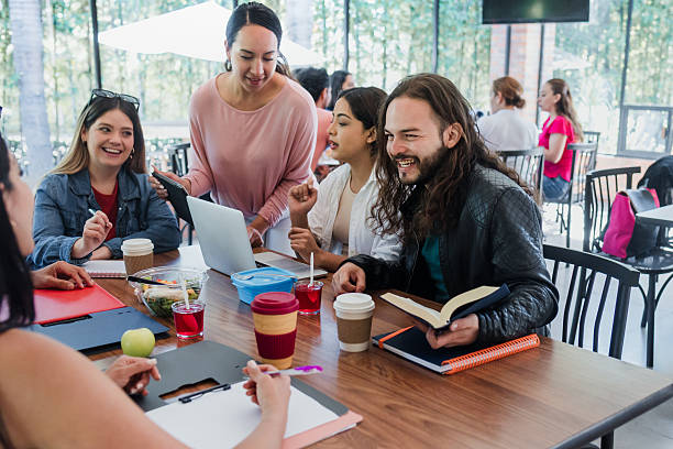 istock Group of Latino university students gathered together studying in cafeteria using laptop and notebook at breakfast time. young hispanic people woman and men in Mexico Latin America 2243882166