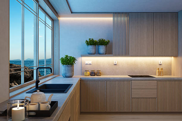 A modern Japandi style kitchen featuring vertical pine wood cabinetry, a light stone counter top, and a neutral color palette that emphasizes simplicity and natural warmth. Dusk blue light streams through large windows, enhancing the textures and materials while creating a calm, inviting atmosphere. Subtle decorative elements—such as ceramic vessels, candles, and clean-lined accessories—add character without disrupting the minimalist flow. This image is ideal for showcasing modern kitchen design, lifestyle content focused on slow living, or editorial features highlighting natural materials and night dusk optimized interiors.