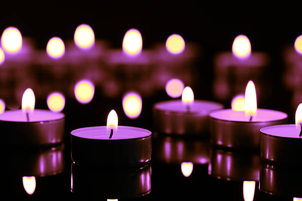 istock Burning violet candle on black background, closeup. Funeral attributes 2243884725