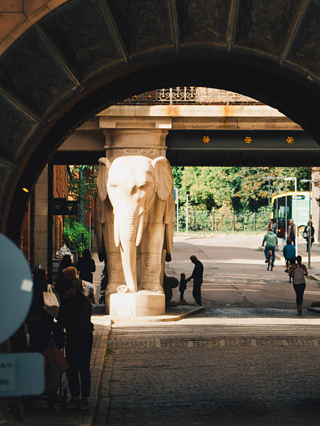 Copenhagen, Denmark – September 14, 2024: Pedestrians and cyclists pass under the historic Elephant Gate with granite elephant sculpture at Carlsberg Byen brewery district.