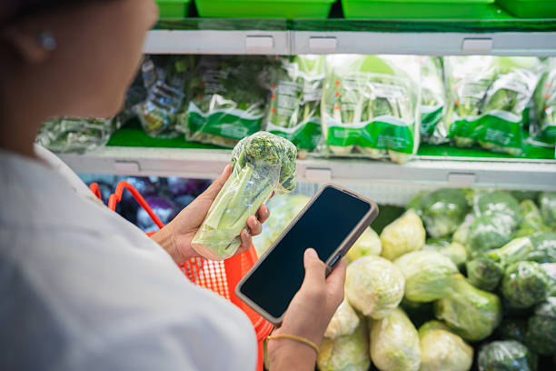istock Woman checking vegetable packaging with smartphone 2243891680