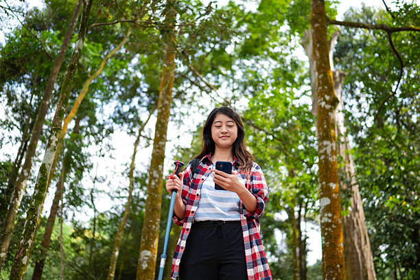 istock Young Asian woman explores trails using her smartphone and hiking Stick 2243899974
