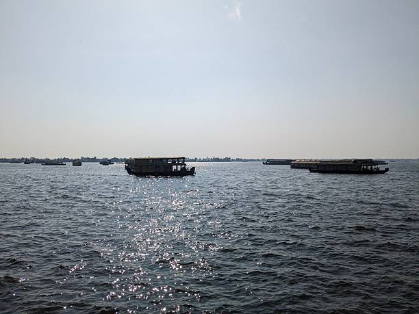 Houseboats sail across sparkling waters under the soft glow of the afternoon sun, casting silhouettes along the shimmering river.