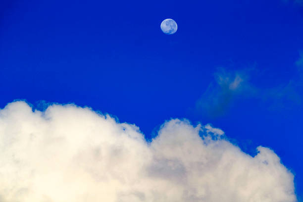 istock The moon peeking through fluffy white clouds 2243903891