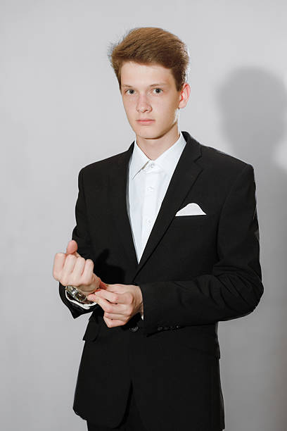 istock Portrait a Young man in a black suit adjusting his jacket in a studio 2243904122