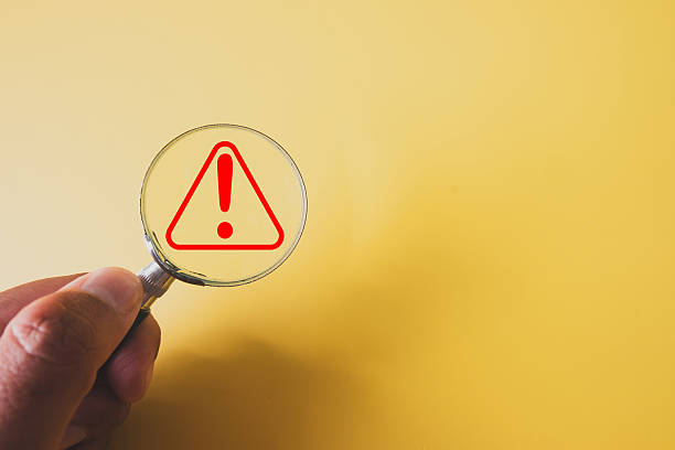 istock Risk Assessment Concept: Hand Holding Magnifier on Warning Alert Icon 2243906578