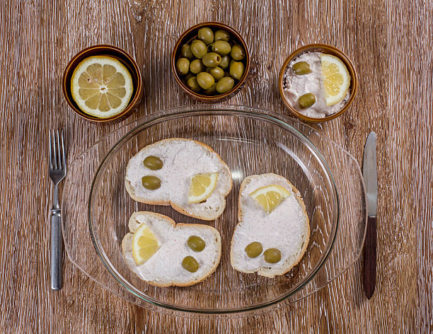Breakfast with taramasalata canape, lemon and green olives on wooden background