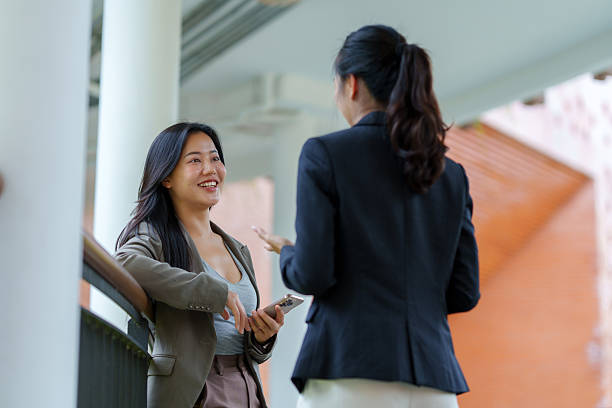 istock Business women having conversation outdoors while holding phone 2243907234