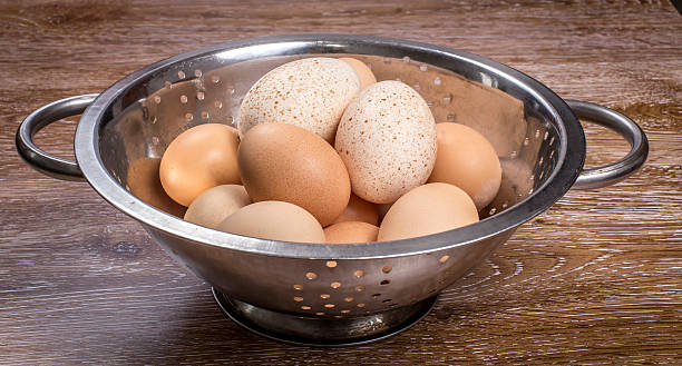 Turkey and chicken eggs in colander on wooden background