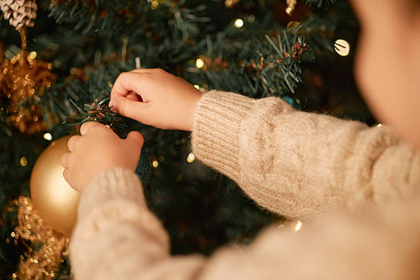 istock Child Decorating Christmas Tree with Ornaments during Holiday Season 2243908264