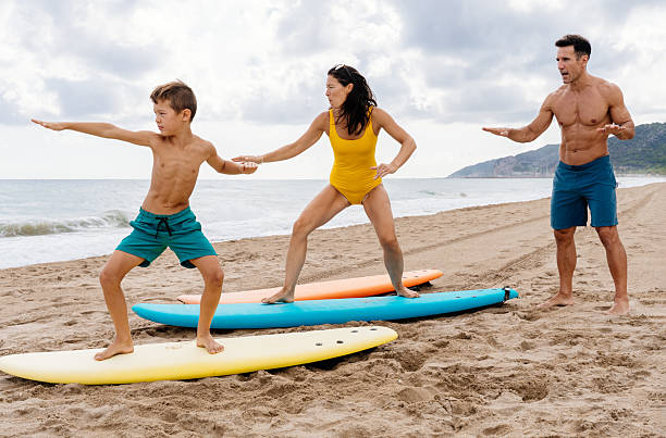 istock Family learning surfing on beach with boards 2243909686