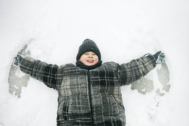 istock Caucasian Child Lying on Snow Making Snow Angel and Smiling Joyfully 2243911107
