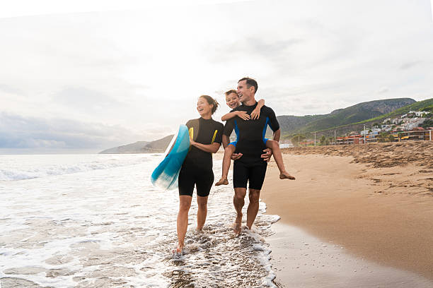 istock Family enjoying beach vacation learning to surf together 2243911145