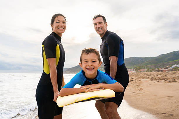 istock Family smiling, learning to surf at beach 2243911224