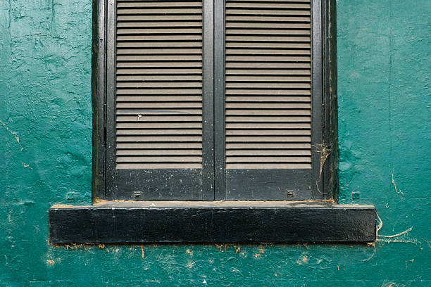 Close-up on old wooden window shutters on a green wall.