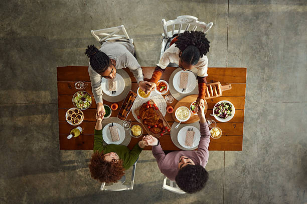 istock Above view of young couples praying before lunch at dining table. 2243912039