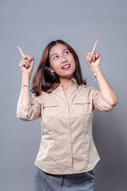 istock Asian Woman Smiling and Pointing Up with Positive Expression 2243912443