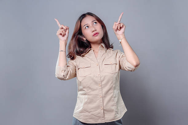 istock Asian Woman Pointing Up with Curious Expression 2243912451