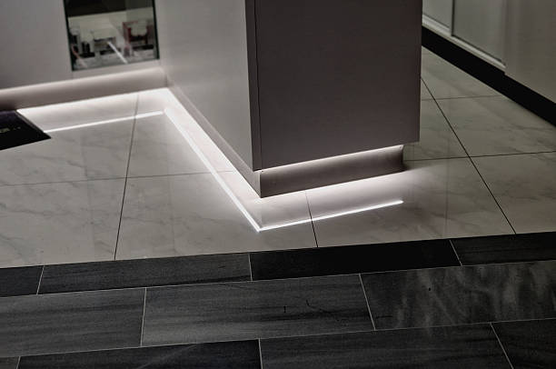 counter with white front lighting and square recessed lights on the table top. Used to present products and illuminate the company logo, tile, tiled floorn gray brown